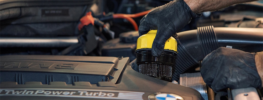Essential Maintenance Tips for European Car Owners. Image of mechanic changing dirty oil filter in bmw car at Advanced European Auto Repair in Franklin, MA.