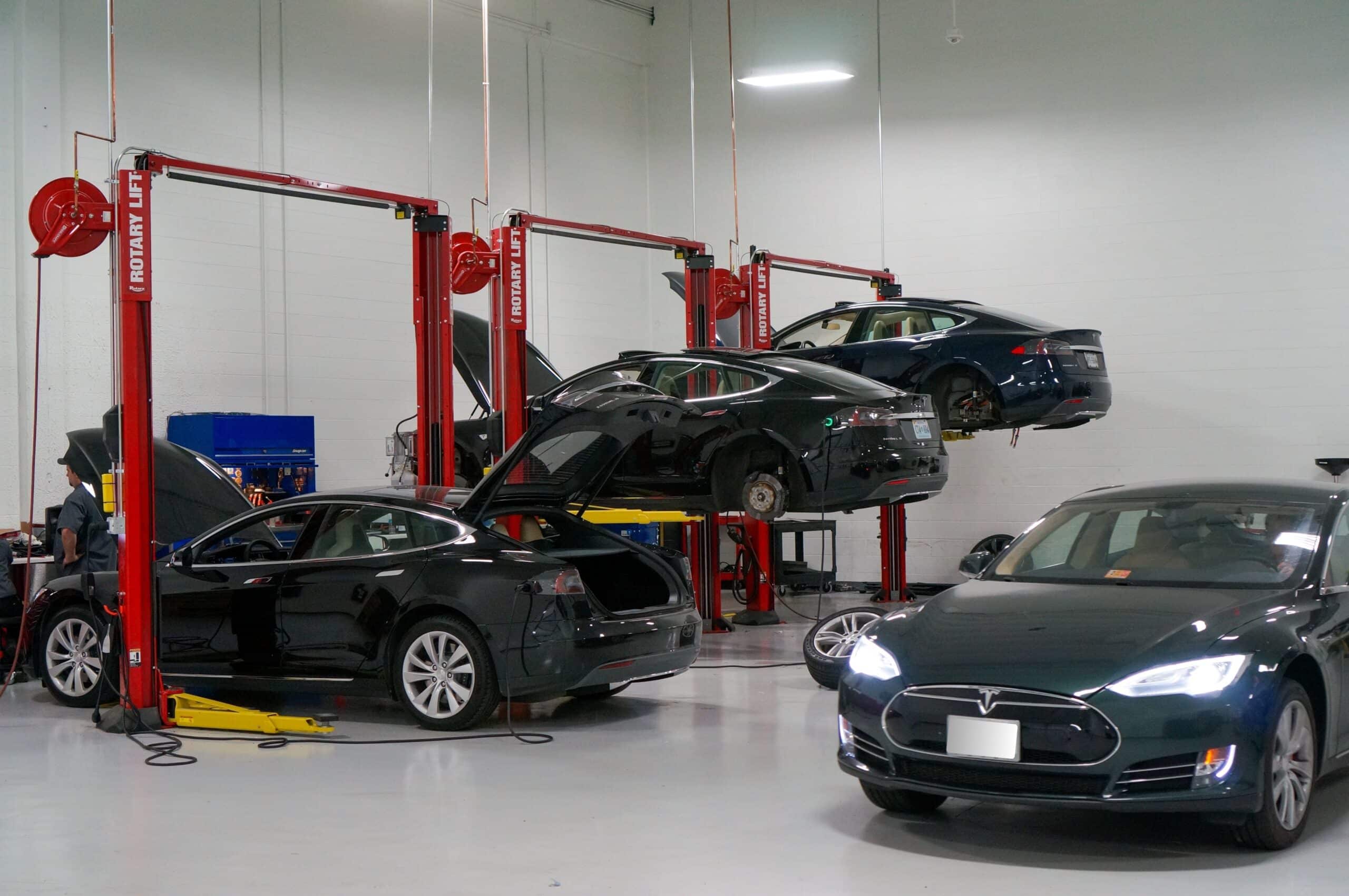 Advanced European Repair | Franklin's Premier Hybrid/EV Repair Specialists. Image of black ev cars on lifts in shop, while one is parked behind them on the shop floor.