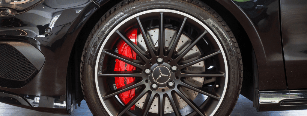 Mercedes brake repair, European auto repair in Franklin, MA by Advanced European Repair. Image of a Mercedes-Benz performance wheel with large drilled rotor and red brake caliper.