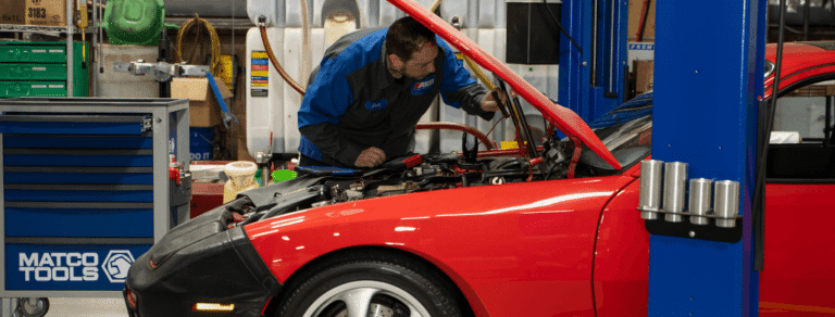 Vehicle diagnostics, auto repair in Franklin, MA, at Advanced European Repair. Automotive technician performing vehicle diagnostics on a red European sports car with the hood open, using professional diagnostic equipment to identify engine and electrical system issues.