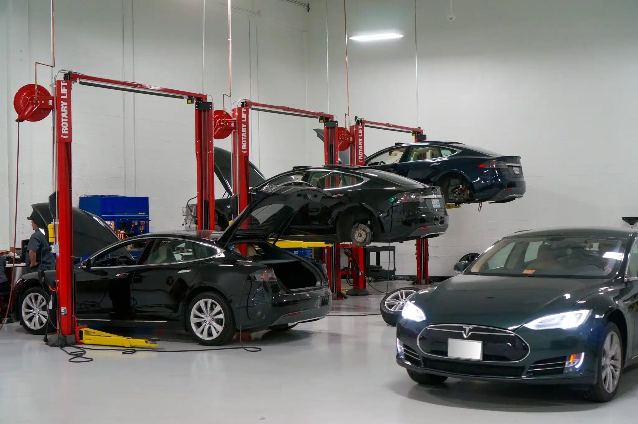 Hybrid and EV maintenance and repair in Franklin, MA, at Advanced European Repair. Image of black ev cars on lifts in shop, while one is parked behind them on the shop floor.