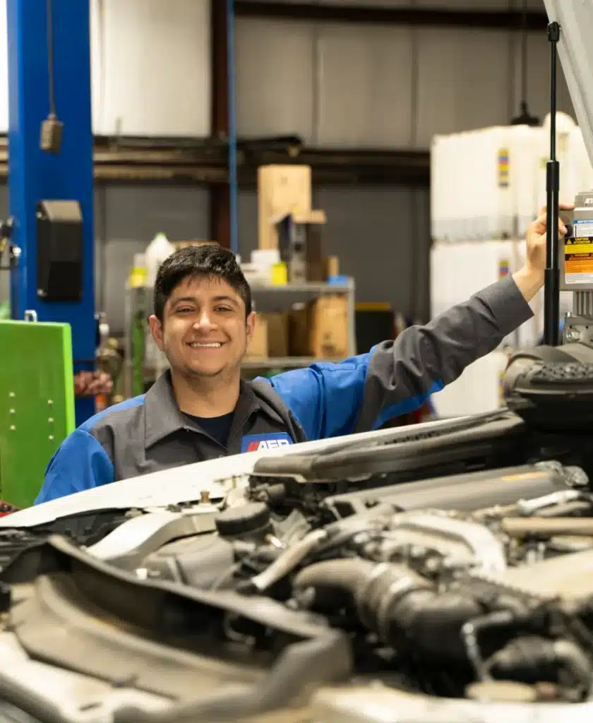 Mechanic smiling beside car engine